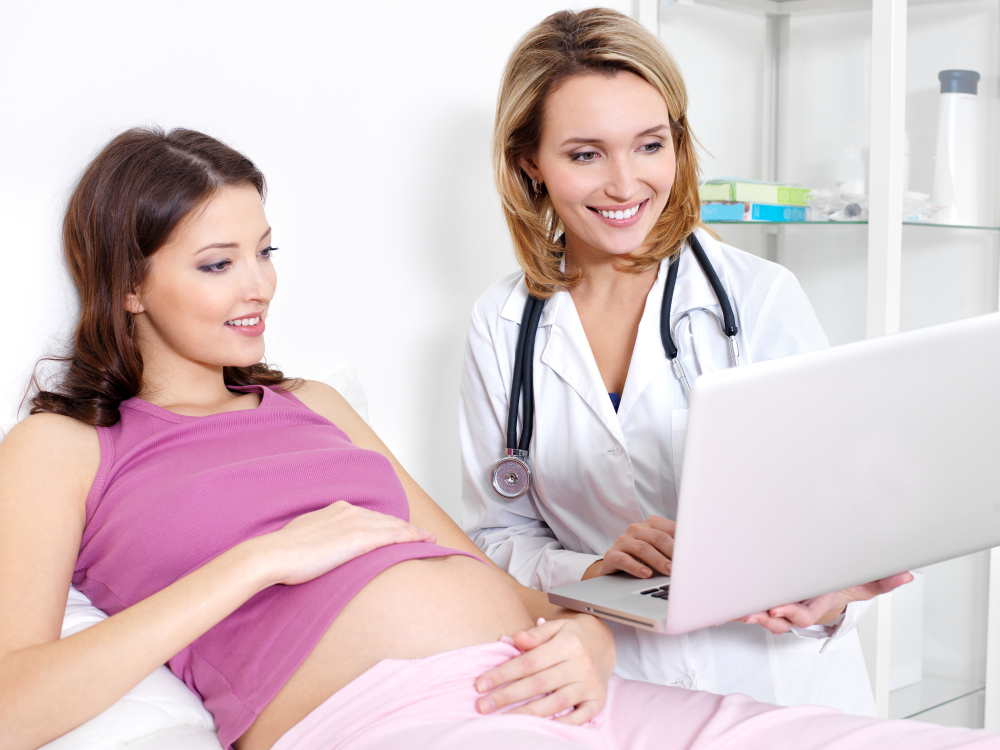 pregnant-young-woman-her-doctor-looking-laptop-indoors